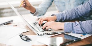 Website developers working using  laptop at the office on wooden table. Film effect